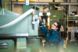 female worker uses machine on manufacturing floor