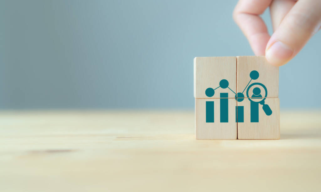 Dark teal customer analytics icon on wooden blocks against a blurred backdrop